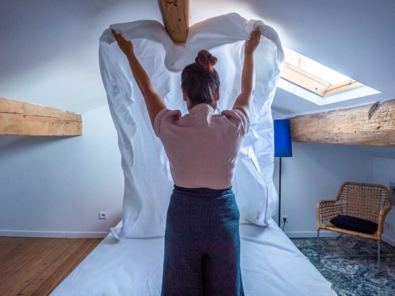 femme de ménage préparant un lit dans un logement Airbnb propre et accueillant